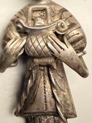 Detail: the lady holding a cross-hatched gold ingot