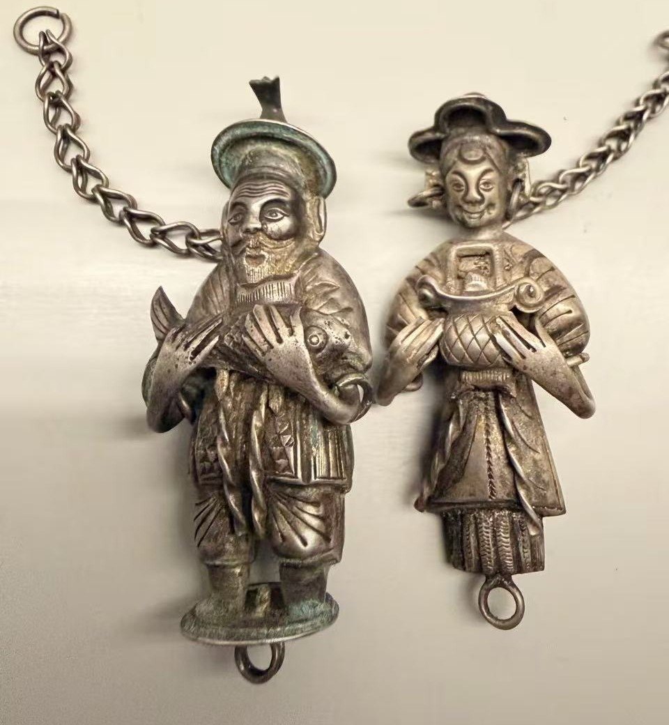The fisherman and the lady pendants side by side, each with a silver chain